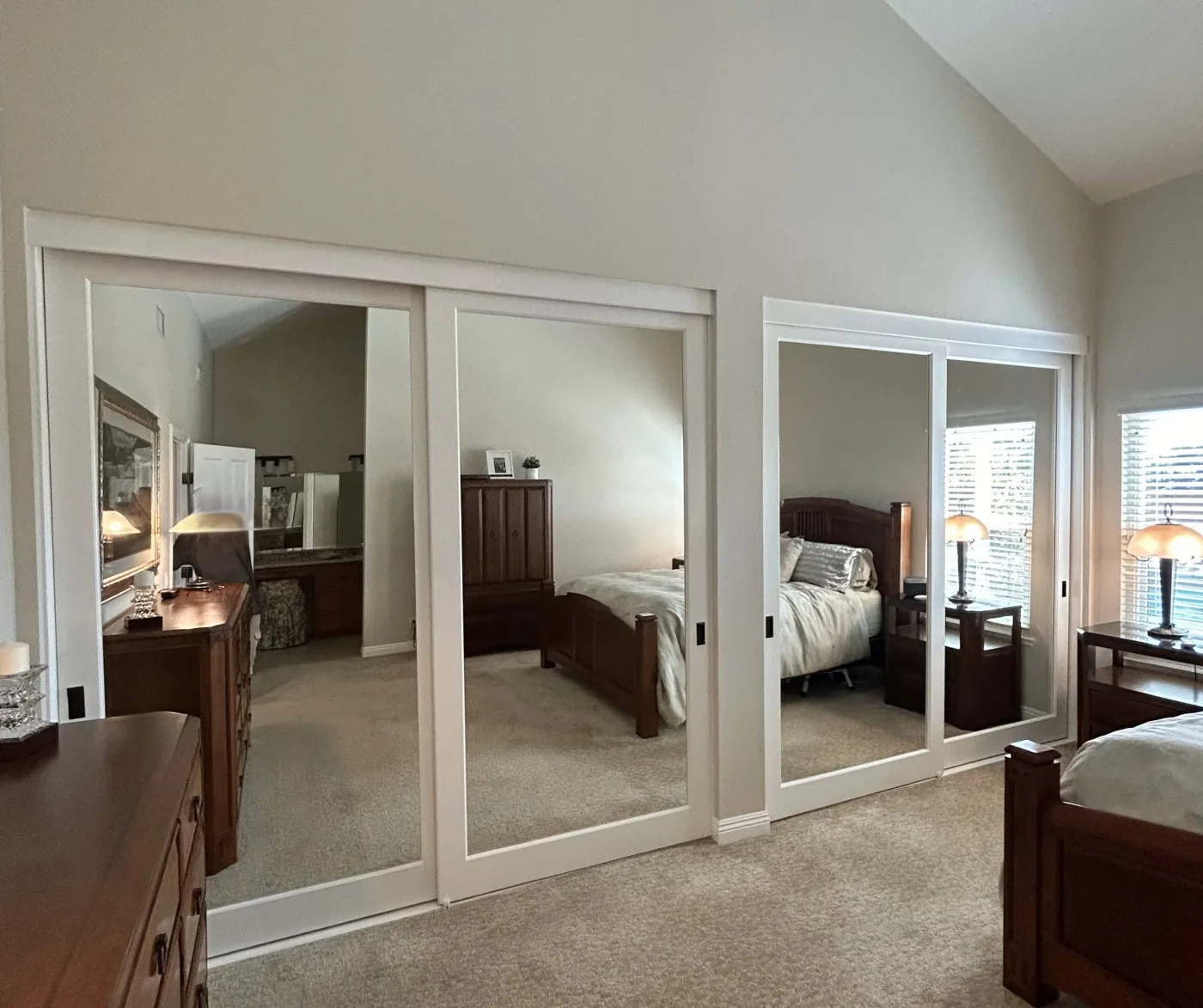 Mirrored sliding closet doors installed side by side in a bedroom