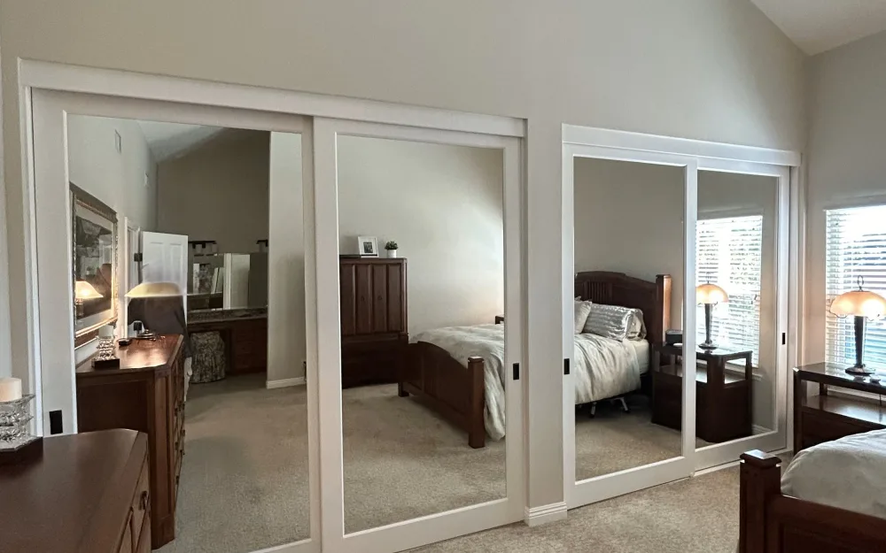 Mirrored sliding closet doors installed side by side in a bedroom