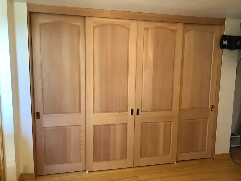 Two-panel raised wood sliding closet doors in a bedroom