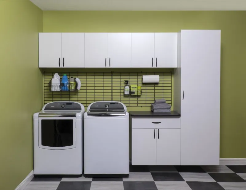 Laundry room with custom white cabinets and countertop over washer and dryer