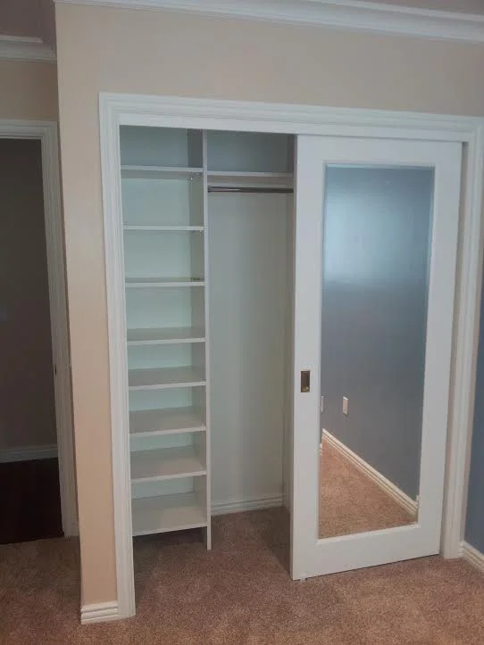 Reach-in closet with sliding mirror door and open shelving