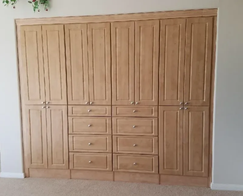 Wood-tone reach-in wardrobe closet with cabinet doors and drawers
