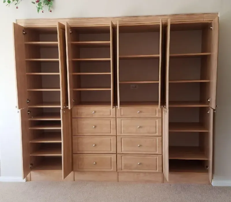 Wood-tone reach-in wardrobe closet with cabinet doors open, showing interior shelving