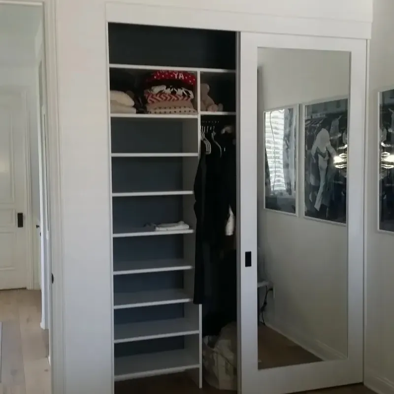 Reach-in closet with sliding mirror door, open shelving and hanging storage