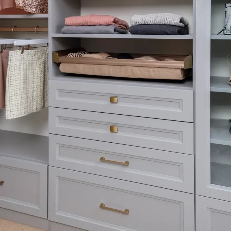 Walk-in closet drawer stack in cloud gray finish with folded sweaters and a jewelry tray