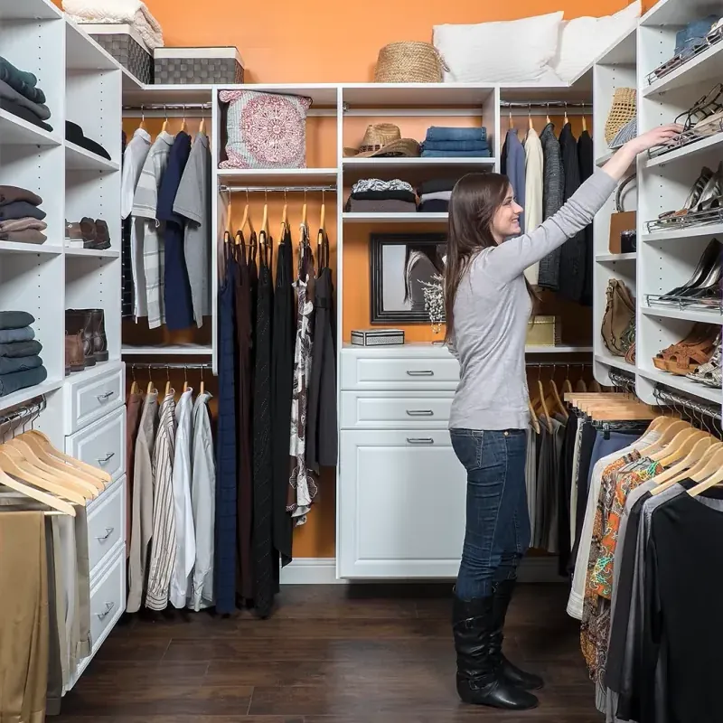 Walk-in closet with vibrant orange accent wall, hanging storage and built-in dresser