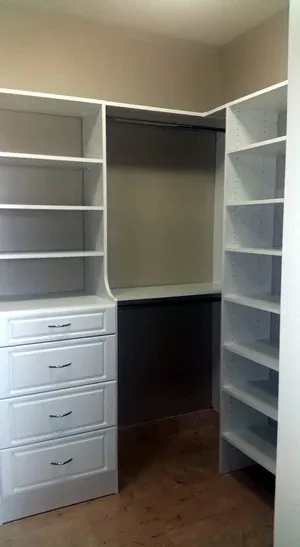 Walk-in closet with corner hanging rods and white drawer stack