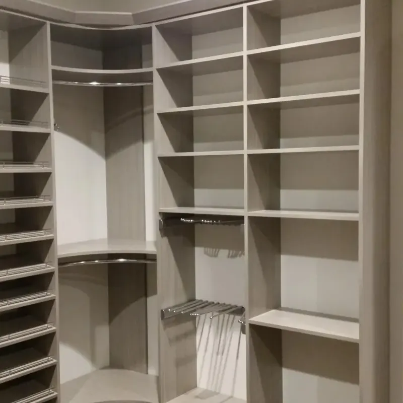 Gray flat-panel corner walk-in closet with shoe shelving and hanging rods