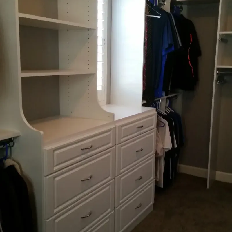 White walk-in closet with center dresser island, mirror and hanging storage